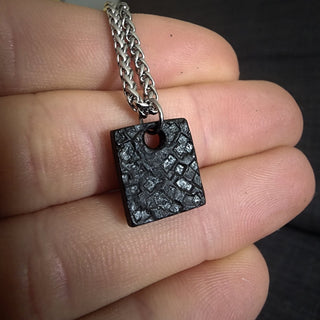 Black Rectangular Stainless Steel Pendant Against Palm