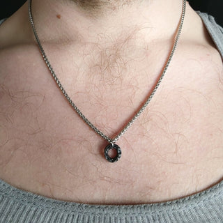 Circlular Textured Black Stainless Steel Pendant on Bare Skin of Sternum