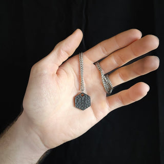 Hexagonal Textured Black Stainless Steel Pendant Against Palm