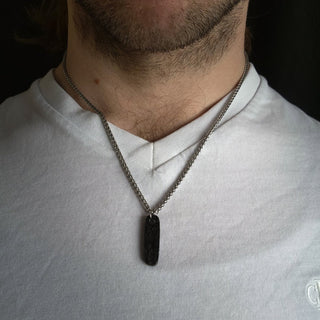 Black Ovular Stainless Steel Pendant on Male's Neck with White Shirt