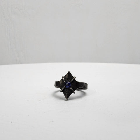 Black stainless steel star ring with a round sapphire set in the center