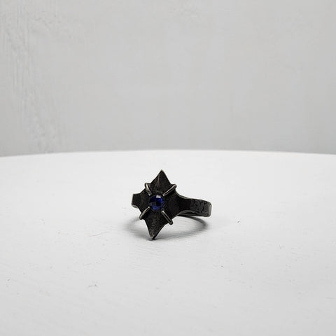 Black stainless steel star ring with a round sapphire set in the center