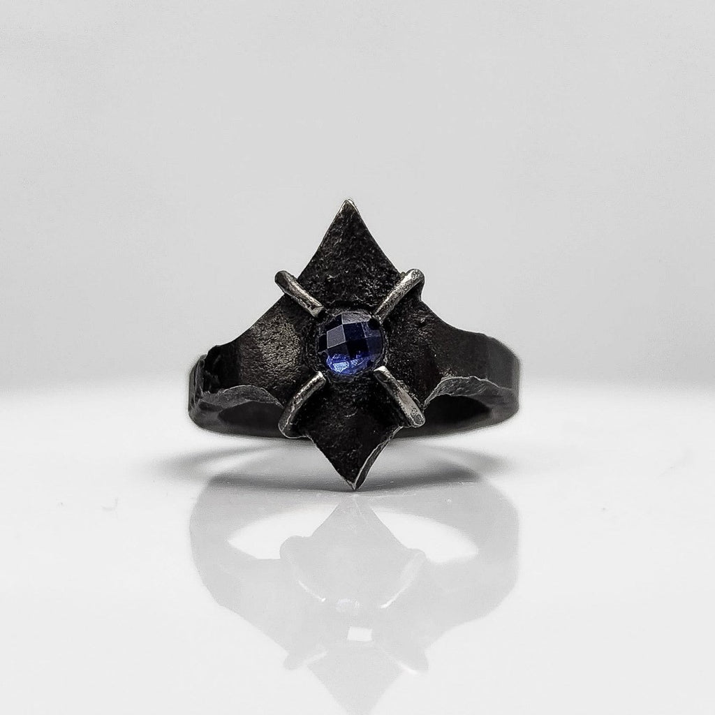 Black stainless steel star ring with a round sapphire set in the center