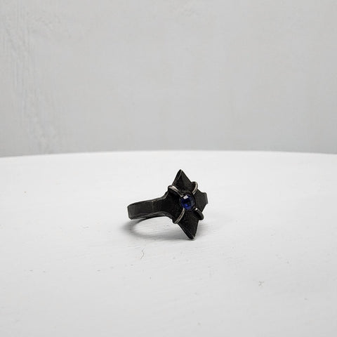 Black stainless steel star ring with a round sapphire set in the center