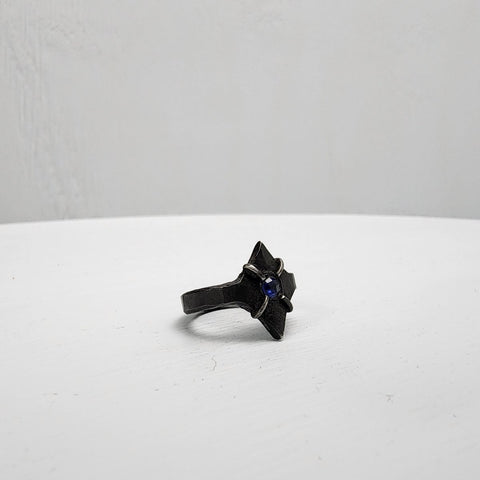 Black stainless steel star ring with a round sapphire set in the center