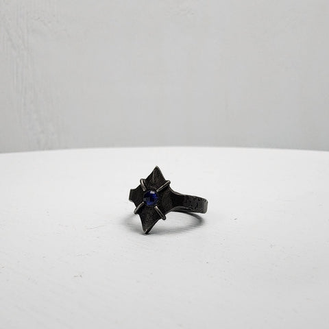 Black stainless steel star ring with a round sapphire set in the center